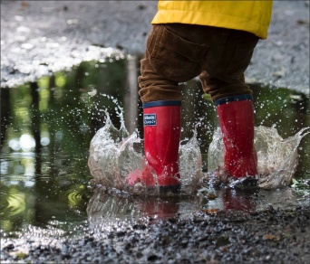 Leanbh óg ina chuid buataisí i lochán uisce